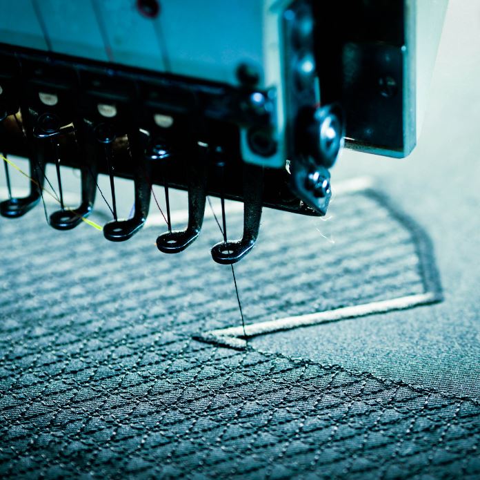 Embroidery machine sewing stitches onto garment